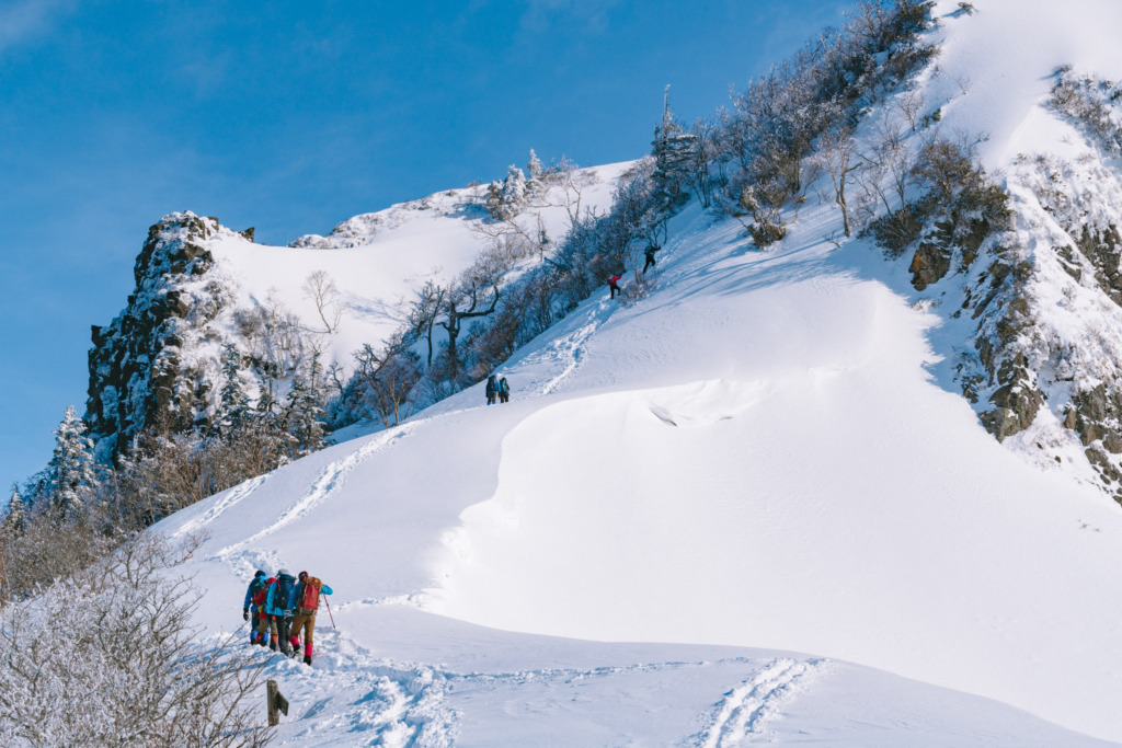 雪の壁にとり付く登山者の列