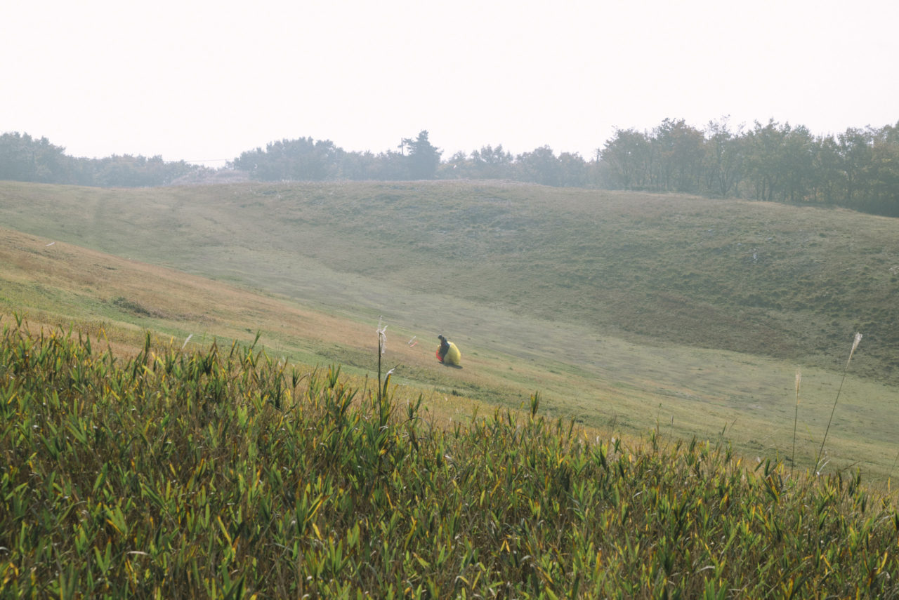 パラシュートをもって坂を上る人