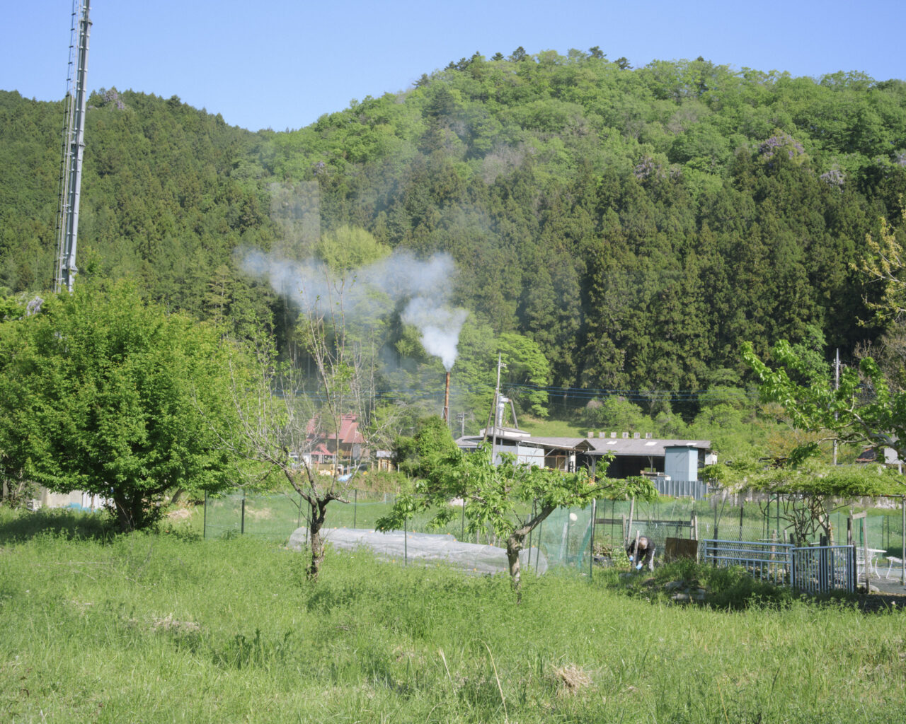 煙を上げる山里の民家